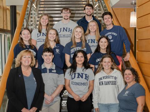 A group photo on the Paul College great hall stairs with all of the 2024 Dean's Ambassadors smiling at the camera alongside Dean Lucy Gilson and Director of Undergraduate Programming Tamara Scapicchio. 
